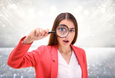 A woman uses a magnifying glass for a closer examination of promotional metal giveaways.